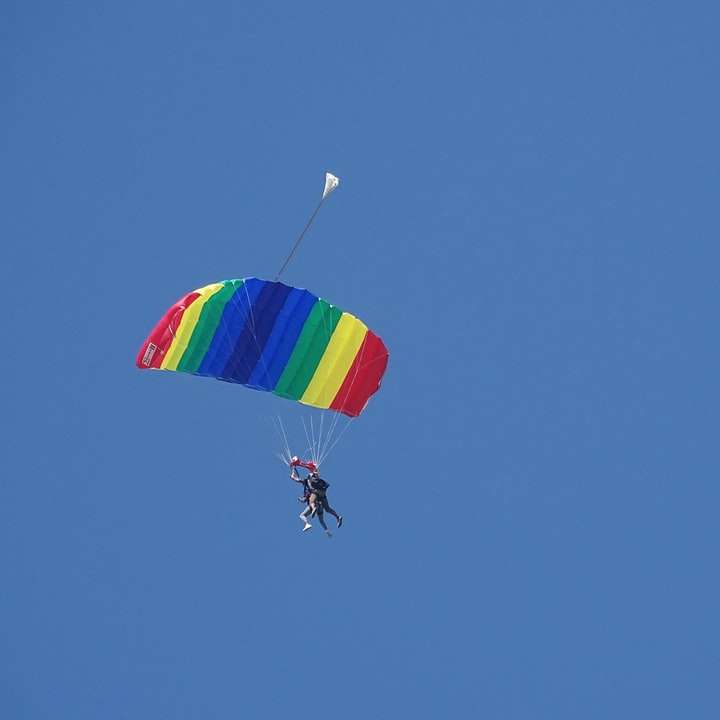 person i fallskärm under blå himmel under dagtid glidande pussel online