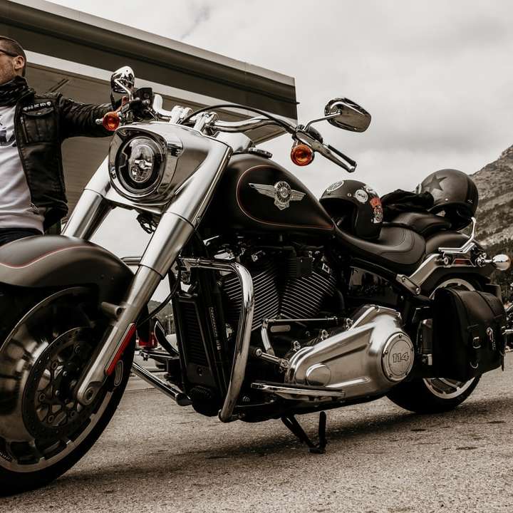 Hombre de chaqueta negra cabalgando sobre una motocicleta cruiser negra rompecabezas en línea