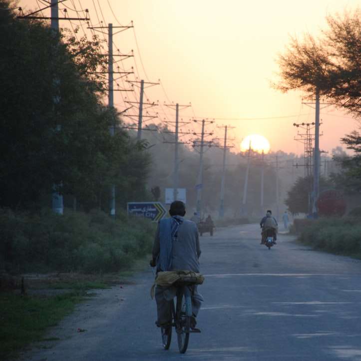 мъж в синьо яке, каращ велосипед по пътя през деня онлайн пъзел