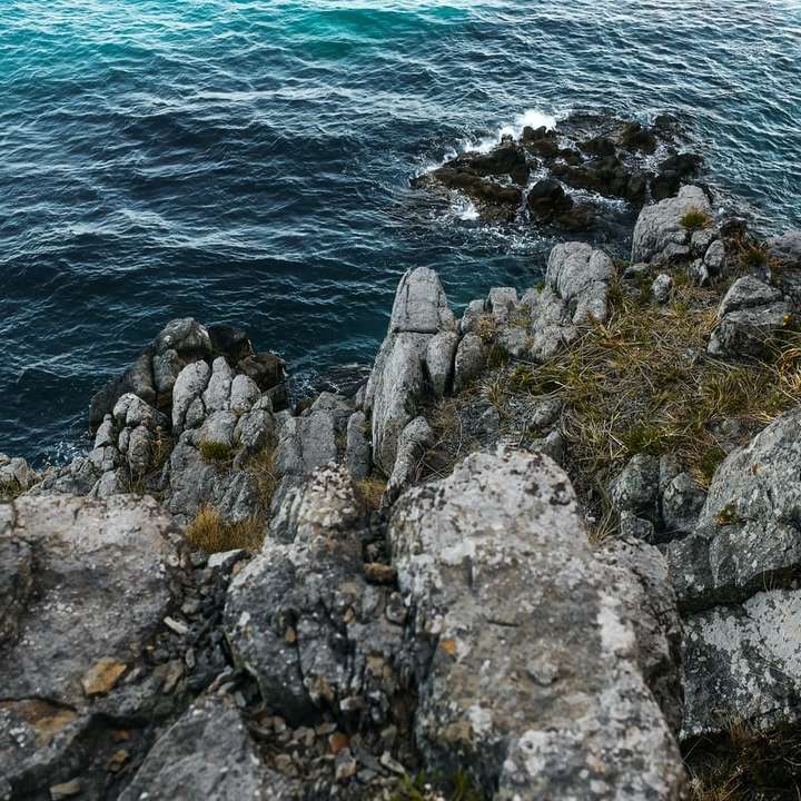 šedý skalní útvar poblíž vodního útvaru během dne posuvné puzzle online