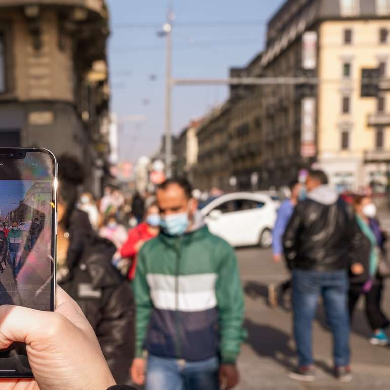 Person hält schwarzes iPhone 5, das Foto des Mannes macht Schiebepuzzle online