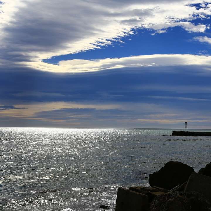 Barco blanco y negro en el mar bajo un cielo azul durante el día rompecabezas en línea