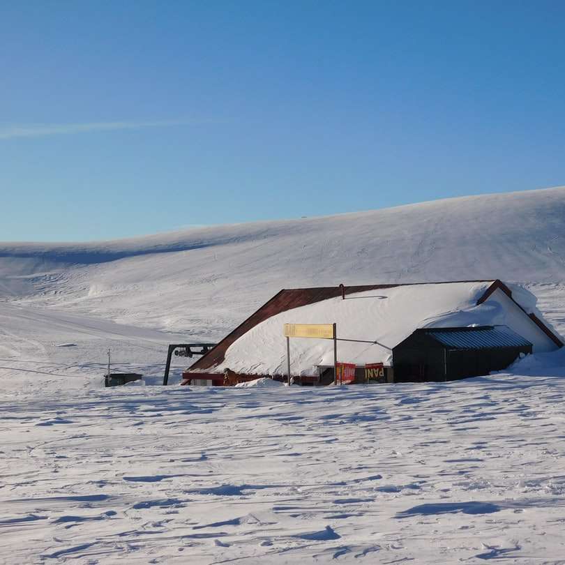 καφέ ξύλινο σπίτι στο χιονισμένο έδαφος κάτω από το γαλάζιο του ουρανού συρόμενο παζλ online