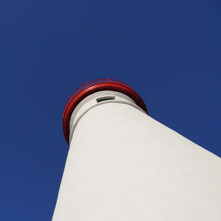 Torre de hormigón blanco y rojo bajo un cielo azul durante el día puzzle deslizante online