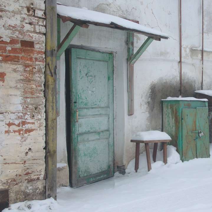 Puerta de madera verde sobre suelo blanco cubierto de nieve puzzle deslizante online