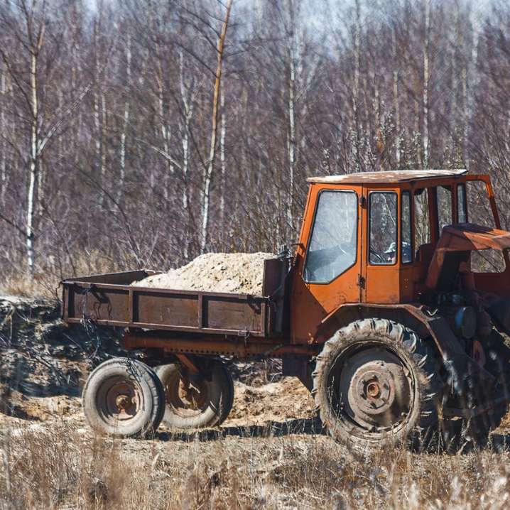 orange och svart traktor på fältet för brunt gräs under dagtid Pussel online