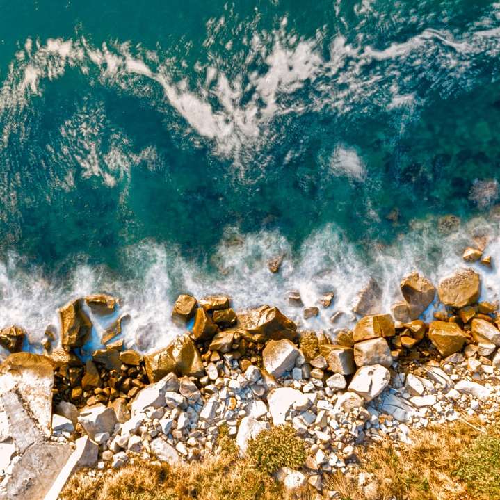 Rocas marrones sobre azul cuerpo de agua durante el día rompecabezas en línea