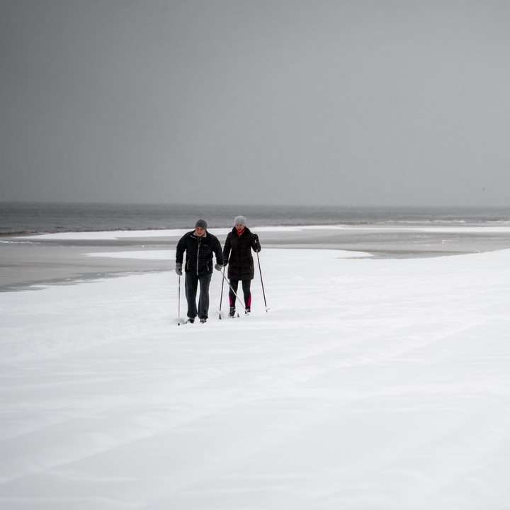 2 personas caminando sobre el campo cubierto de nieve durante el día puzzle deslizante online