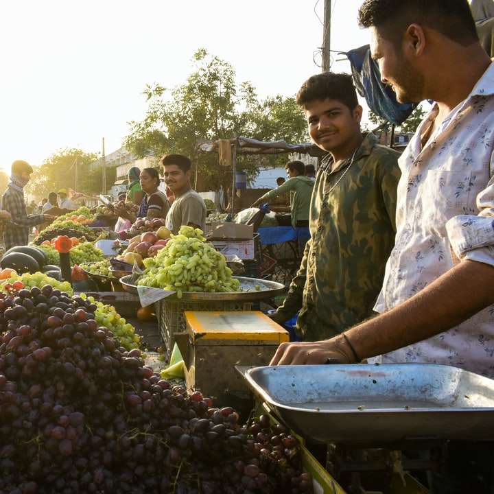 άτομα που στέκονται κοντά σε φρούτα στέκονται κατά τη διάρκεια της ημέρας συρόμενο παζλ online