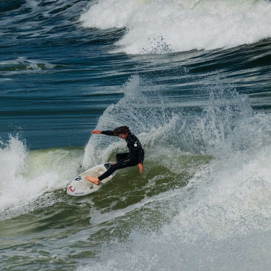 Hombre surfeando sobre las olas del mar durante el día rompecabezas en línea