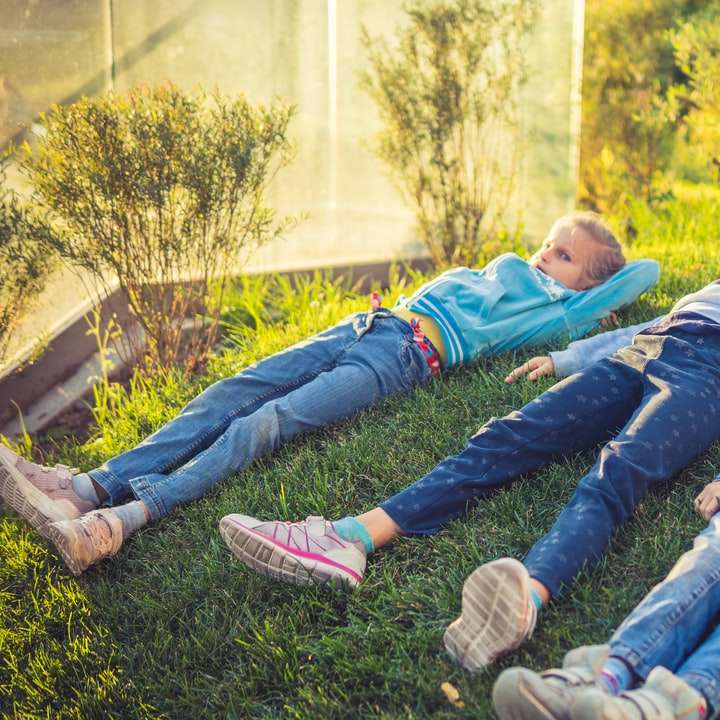 2 niños recostados sobre el campo de hierba verde durante el día puzzle deslizante online