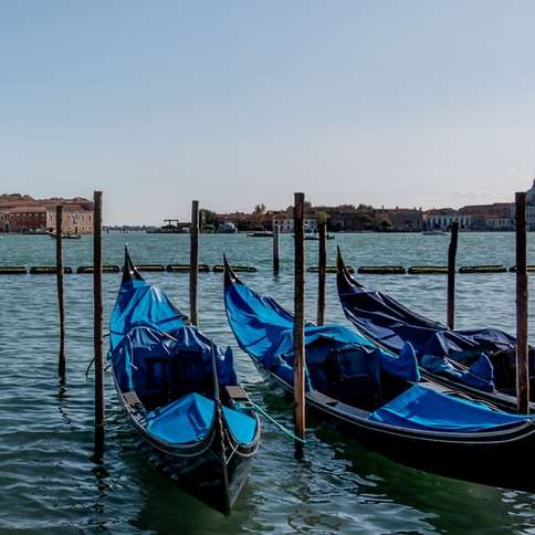 kék és fekete csónak a víz közelében barna beton épület online puzzle