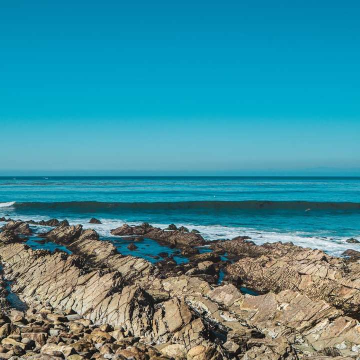 hnědé skalnaté pobřeží poblíž vodní plochy během dne online puzzle