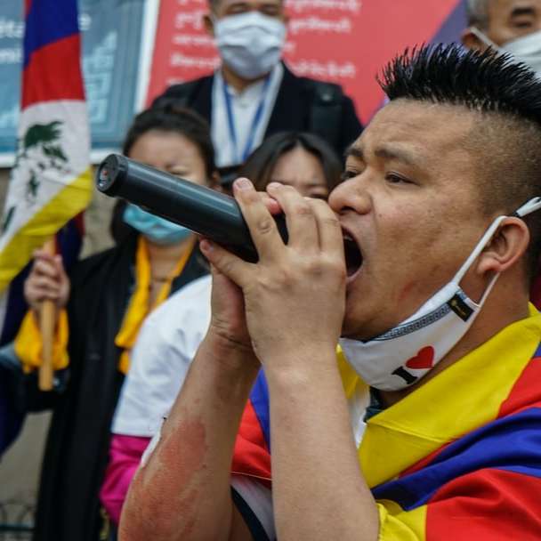 мъж в червена и жълта риза поло, държащ микрофон онлайн пъзел