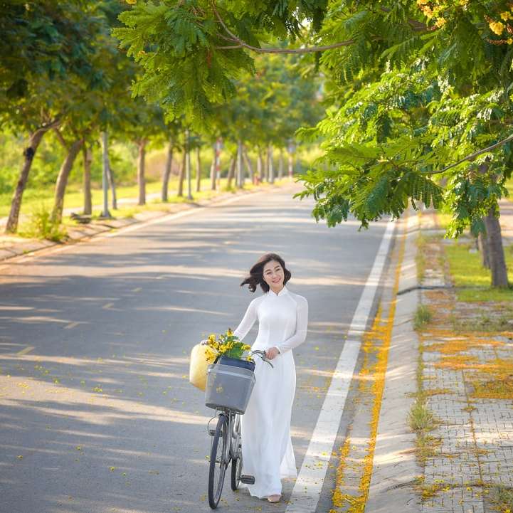 donna in camicia bianca a maniche lunghe in bicicletta sulla strada puzzle scorrevole online