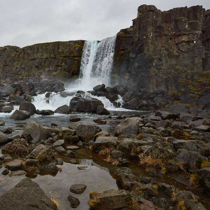 brązowa formacja skalna w pobliżu wodospadów pod białym niebem puzzle przesuwne online