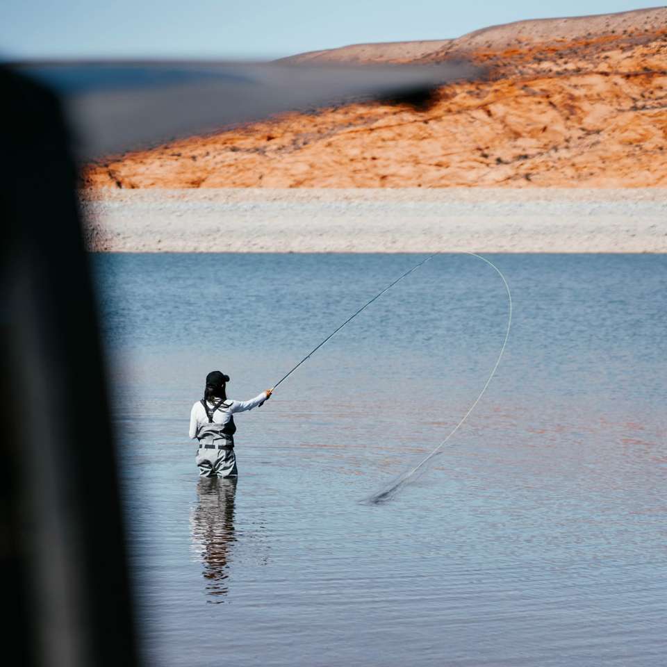 Hombre de chaqueta negra pescando en el mar durante el día rompecabezas en línea