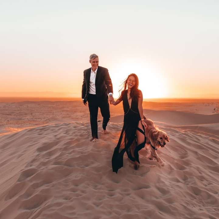 2 donne e un uomo in piedi sulla sabbia marrone durante il giorno puzzle scorrevole online