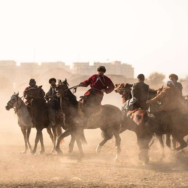 хора, яздещи коне върху кафяв пясък през деня плъзгащ се пъзел онлайн