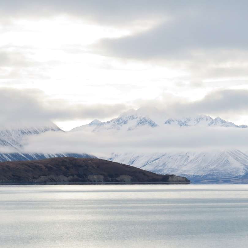 άσπρα σύννεφα πάνω από τη λίμνη και τα βουνά συρόμενο παζλ online