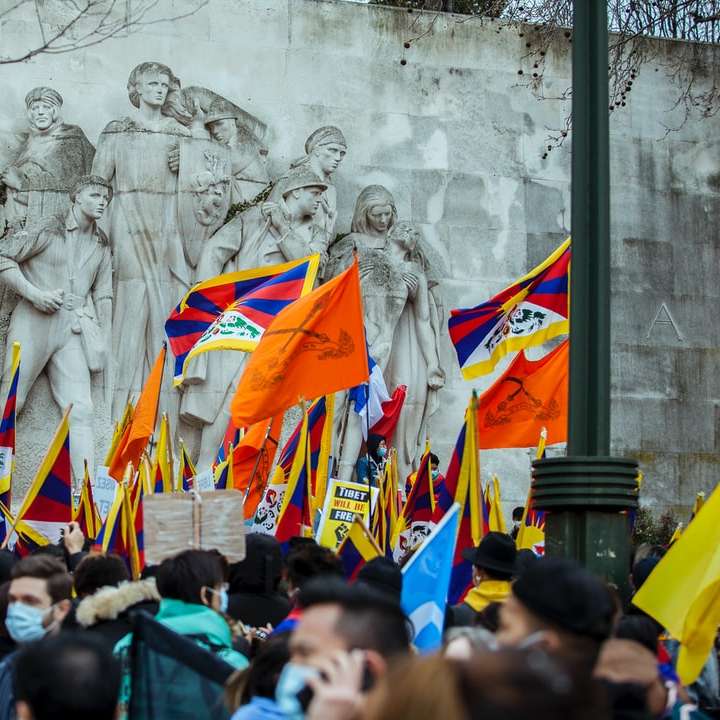 ludzie gromadzący się przed białą betonową ścianą z flagami puzzle przesuwne online