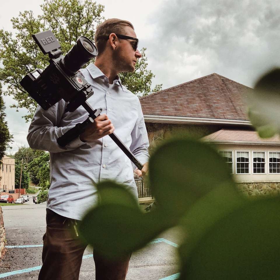 Mann im grauen Hemd, das Kamera hält Online-Puzzle