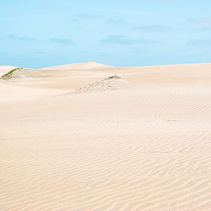 brun sand under blå himmel under dagtid glidande pussel online