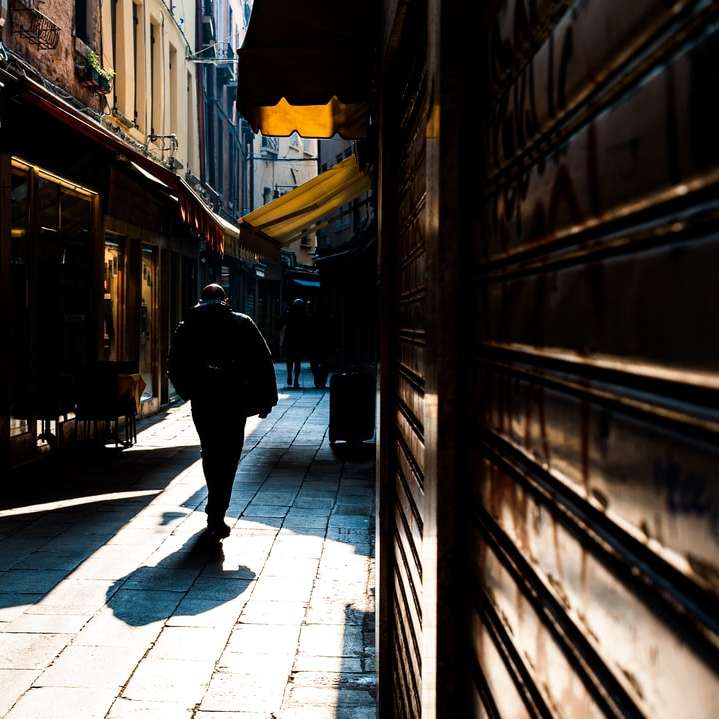 mężczyzna w czarnej kurtce, chodzenie po chodniku w ciągu dnia puzzle przesuwne online