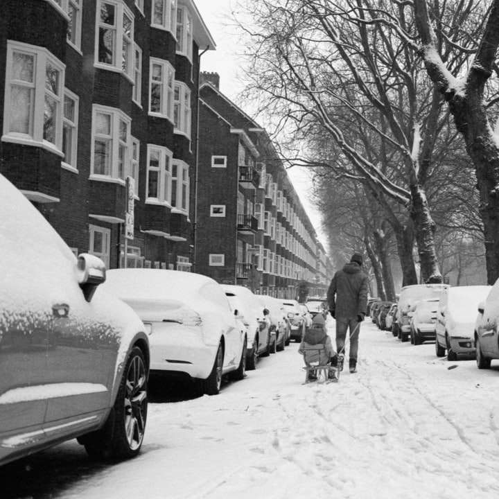 Homme en veste noire marchant sur route couverte de neige puzzle en ligne