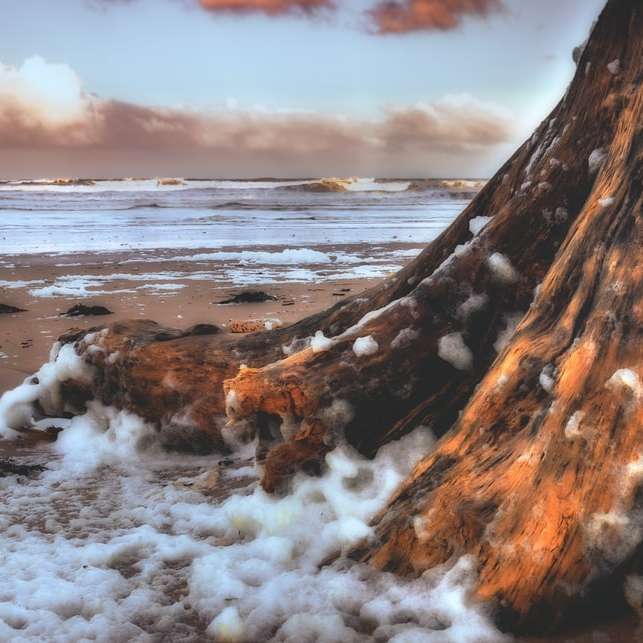 bruine rotsformatie op zee onder witte wolken schuifpuzzel online