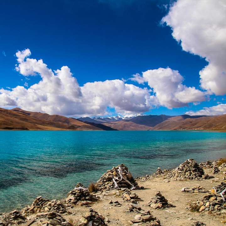 bruine berg dichtbij waterlichaam onder blauwe hemel schuifpuzzel online