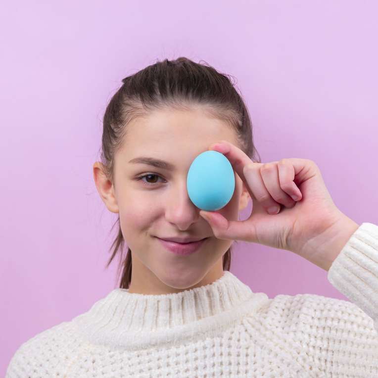 woman in white sweater holding blue egg sliding puzzle online