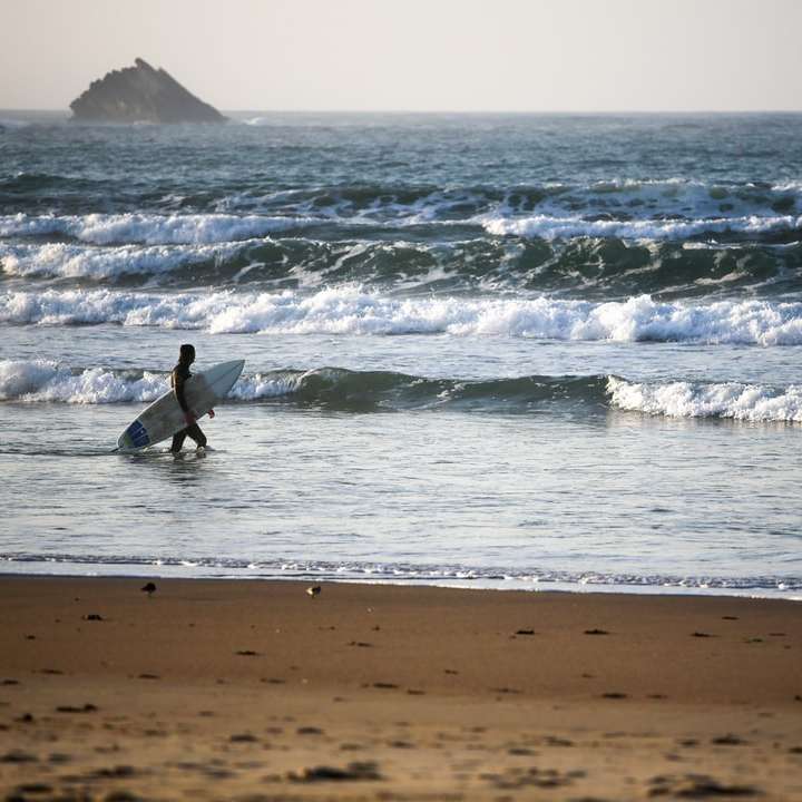 Човек в черен мокър костюм сърфиране на морските вълни през деня плъзгащ се пъзел онлайн