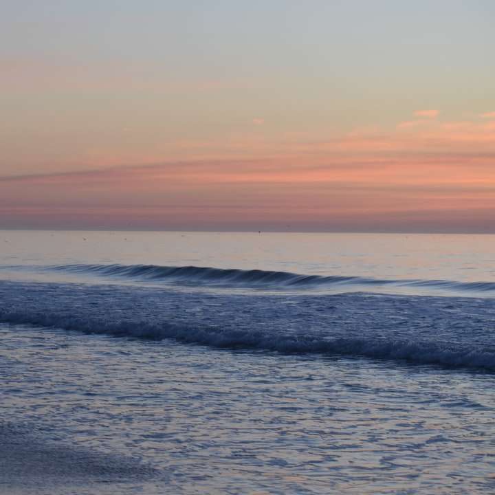 Τα κύματα των ωκεανών συντρίβουν στην ακτή κατά τη διάρκεια του ηλιοβασιλέματος συρόμενο παζλ online