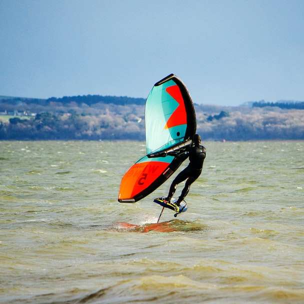 man in black wet suit riding orange kayak on sea sliding puzzle online