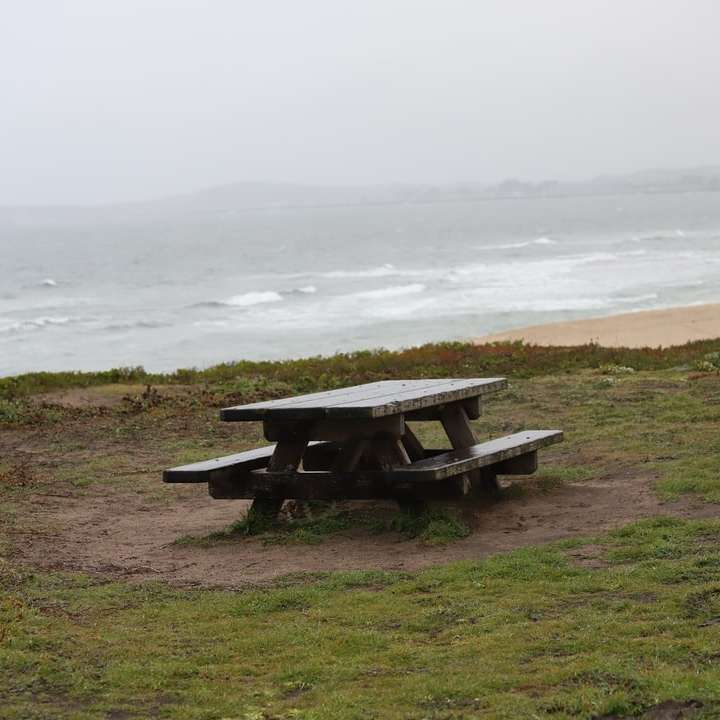 коричневый деревянный стол для пикника на поле зеленой травы возле тела онлайн-пазл