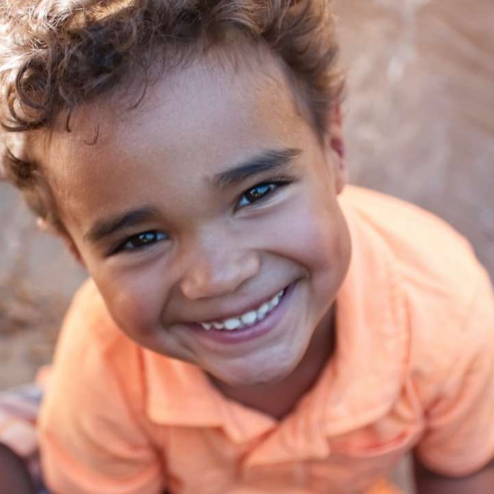 Chłopiec w pomarańczowej koszulce polo uśmiecha się puzzle przesuwne online
