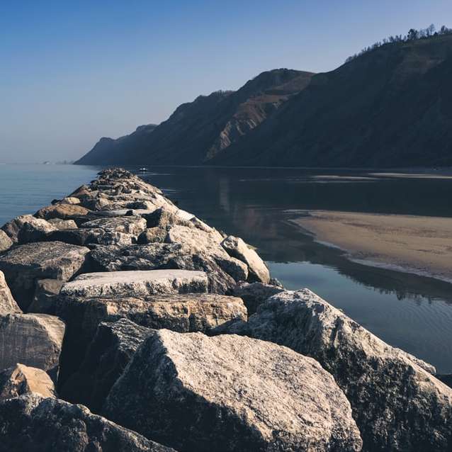 Szary skalisty brzeg w pobliżu wody w ciągu dnia puzzle przesuwne online