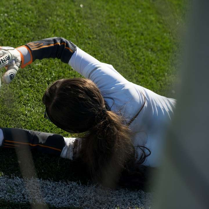 Девушка в белой рубашке с длинным рукавом играет в футбол на поле онлайн-пазл