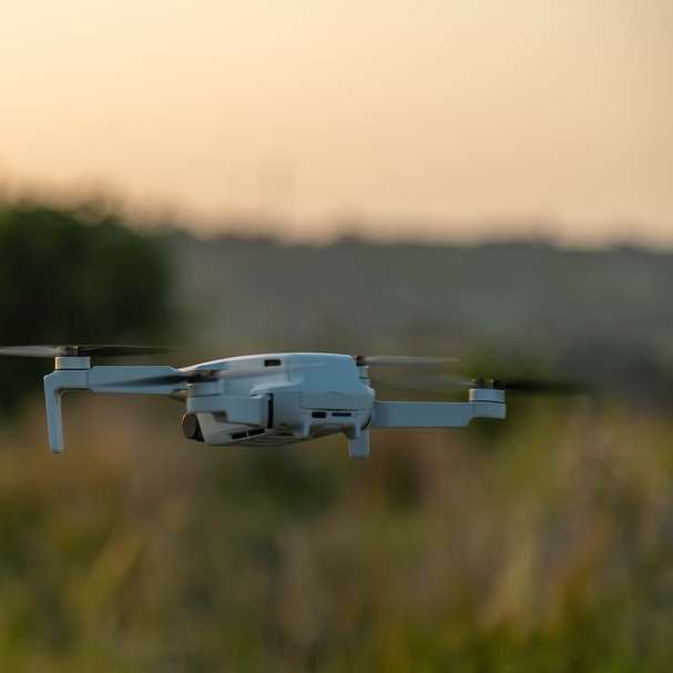Drona albă zboară peste câmpul de iarbă verde în timpul zilei alunecare puzzle online