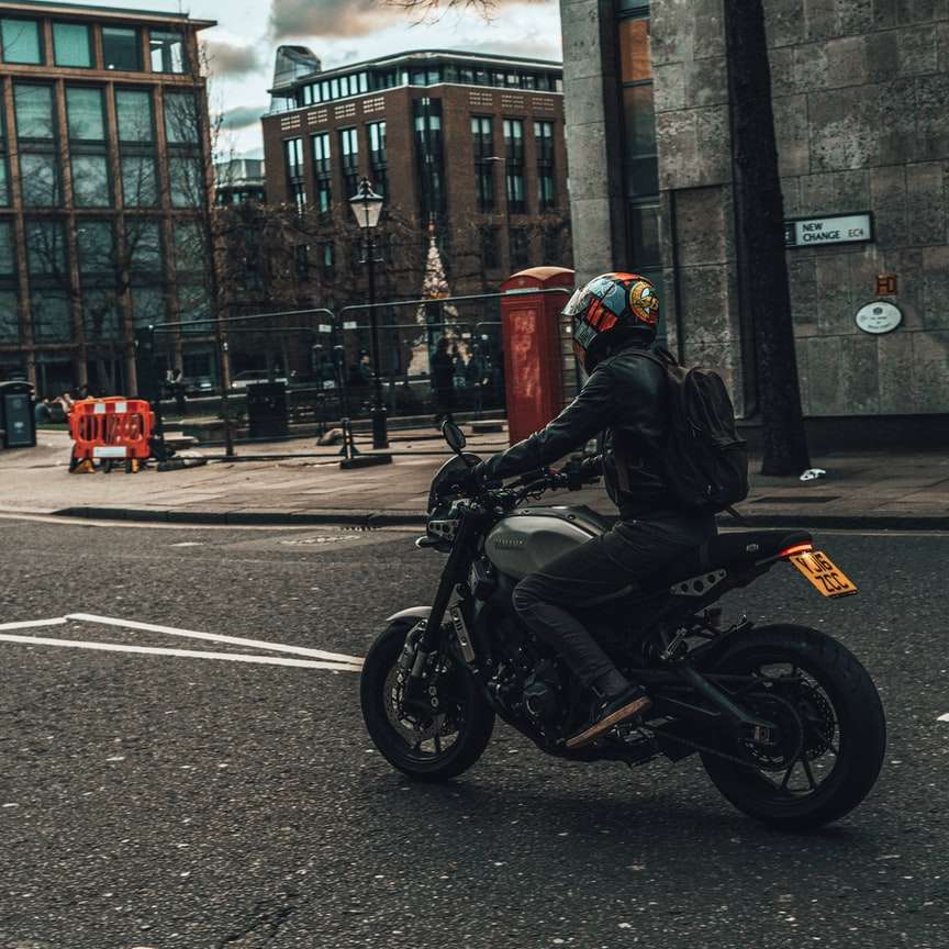 Човек в черната мотоциклет каска езда мотоциклет по пътя плъзгащ се пъзел онлайн