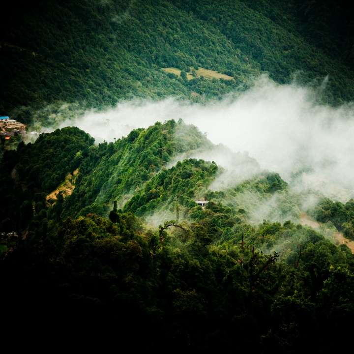 Grönt berg med vita moln under dagtid glidande pussel online