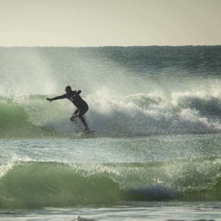 човек сърфира върху морските вълни през деня плъзгащ се пъзел онлайн