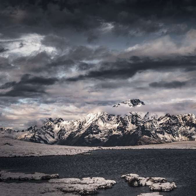 Zasněžené hory u těla vody pod zatažené obloze posuvné puzzle online