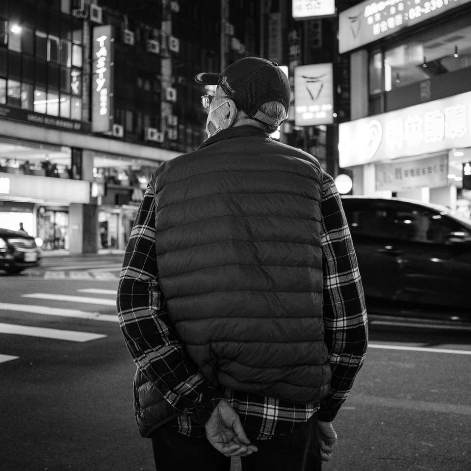 Човек в черно и бяло платно яке стои на тротоара онлайн пъзел