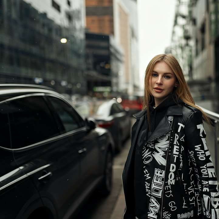 Vrouw in zwart jasje die zich naast zwarte auto bevindt schuifpuzzel online