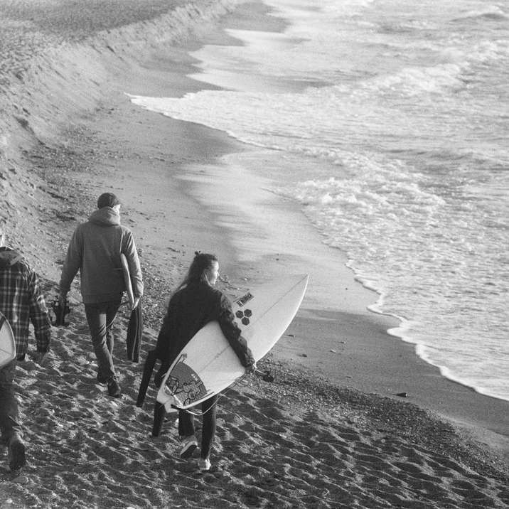 фотографія у відтінках сірого, на якій чоловік і жінка тримають дошку для серфінгу онлайн пазл