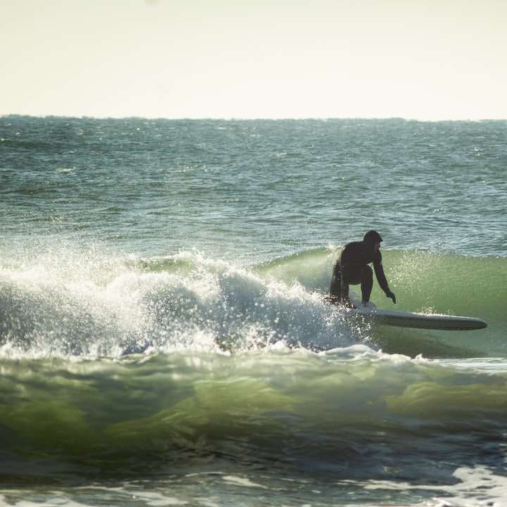 човек сърфира върху морските вълни през деня плъзгащ се пъзел онлайн
