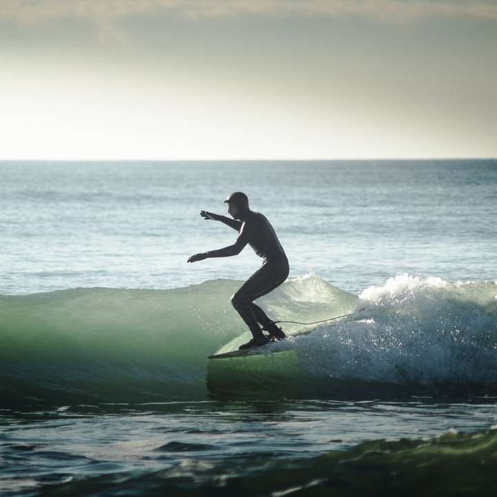Mann, der an der Tageszeit auf Seewellen surft Schiebepuzzle online