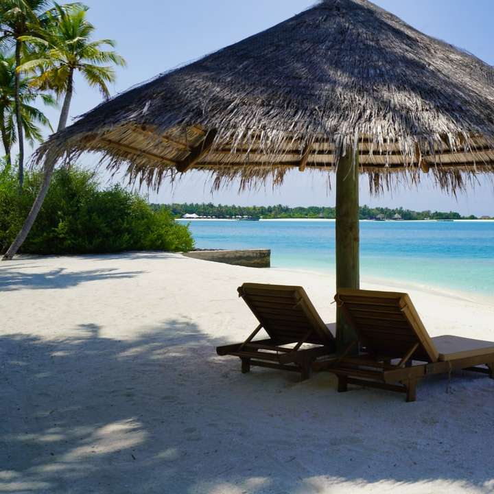 Cadeiras de lounge de madeira marrom na praia da praia durante o dia puzzle deslizante online